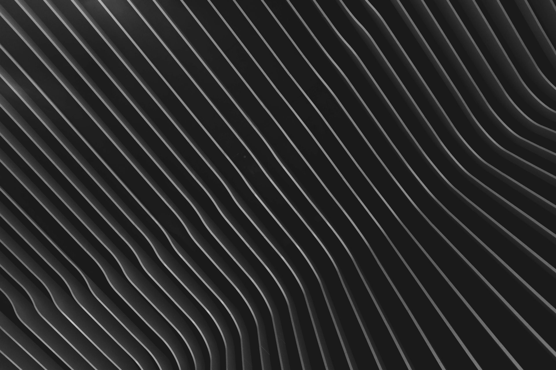 Diagonal wavy lines, grayscale, creating a textured pattern, possibly a metal surface.