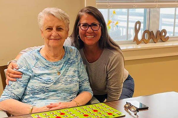 Two women are posing for a picture while sitting at a table.