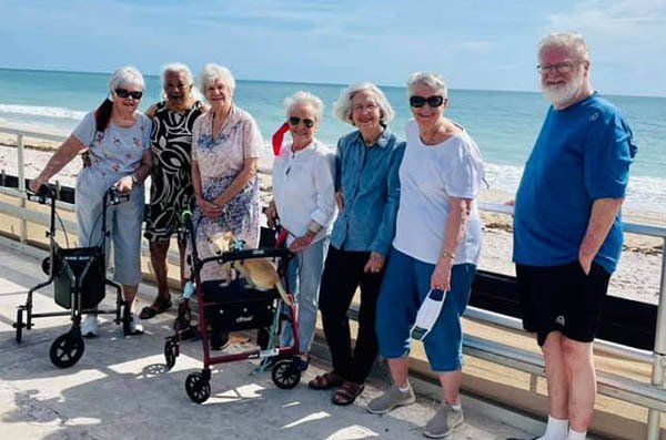 A group of elderly people standing next to each other on a beach.