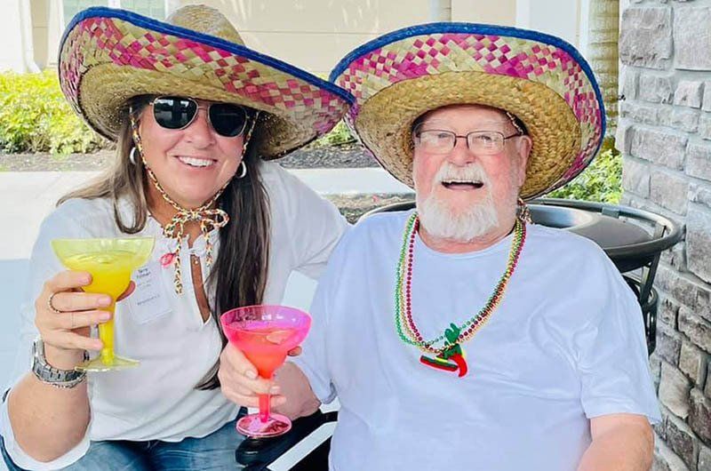 A man and a woman wearing sombrero hats are holding drinks.