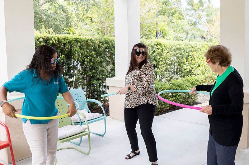 Three women are playing with hula hoops on a porch.