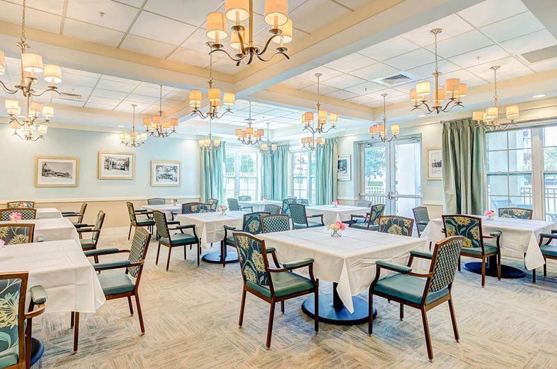 A large dining room with tables and chairs and chandeliers.