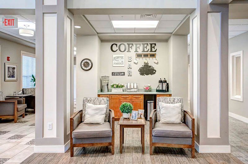 There is a coffee bar in the middle of the room with chairs and a table.
