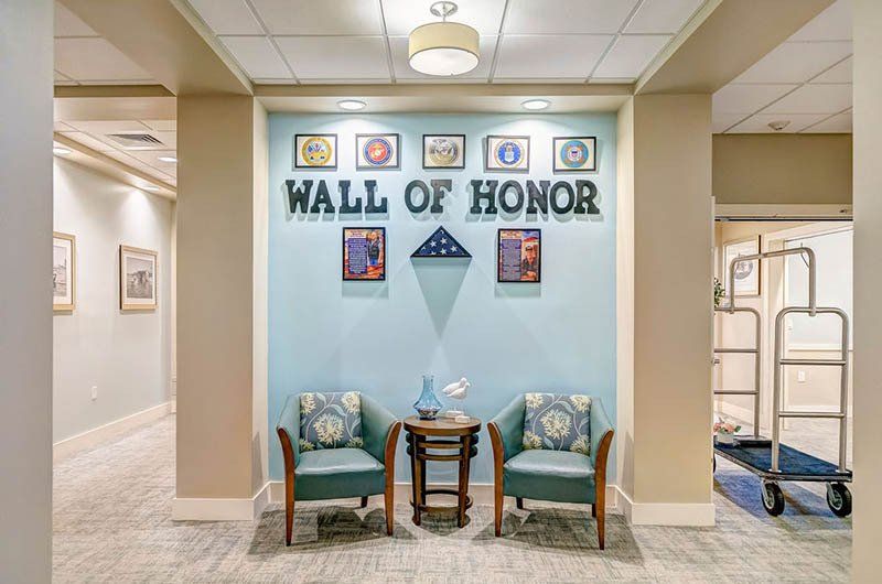 A hallway with two chairs and a wall of honor.