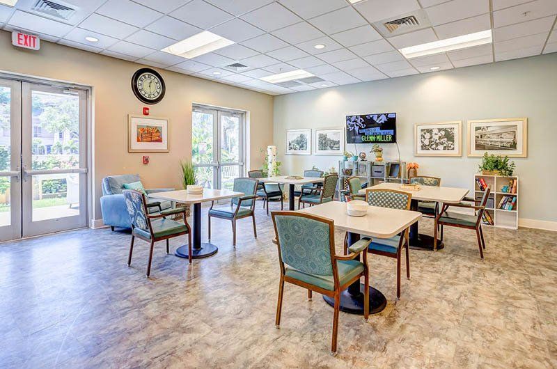 A large room with tables and chairs in a nursing home.