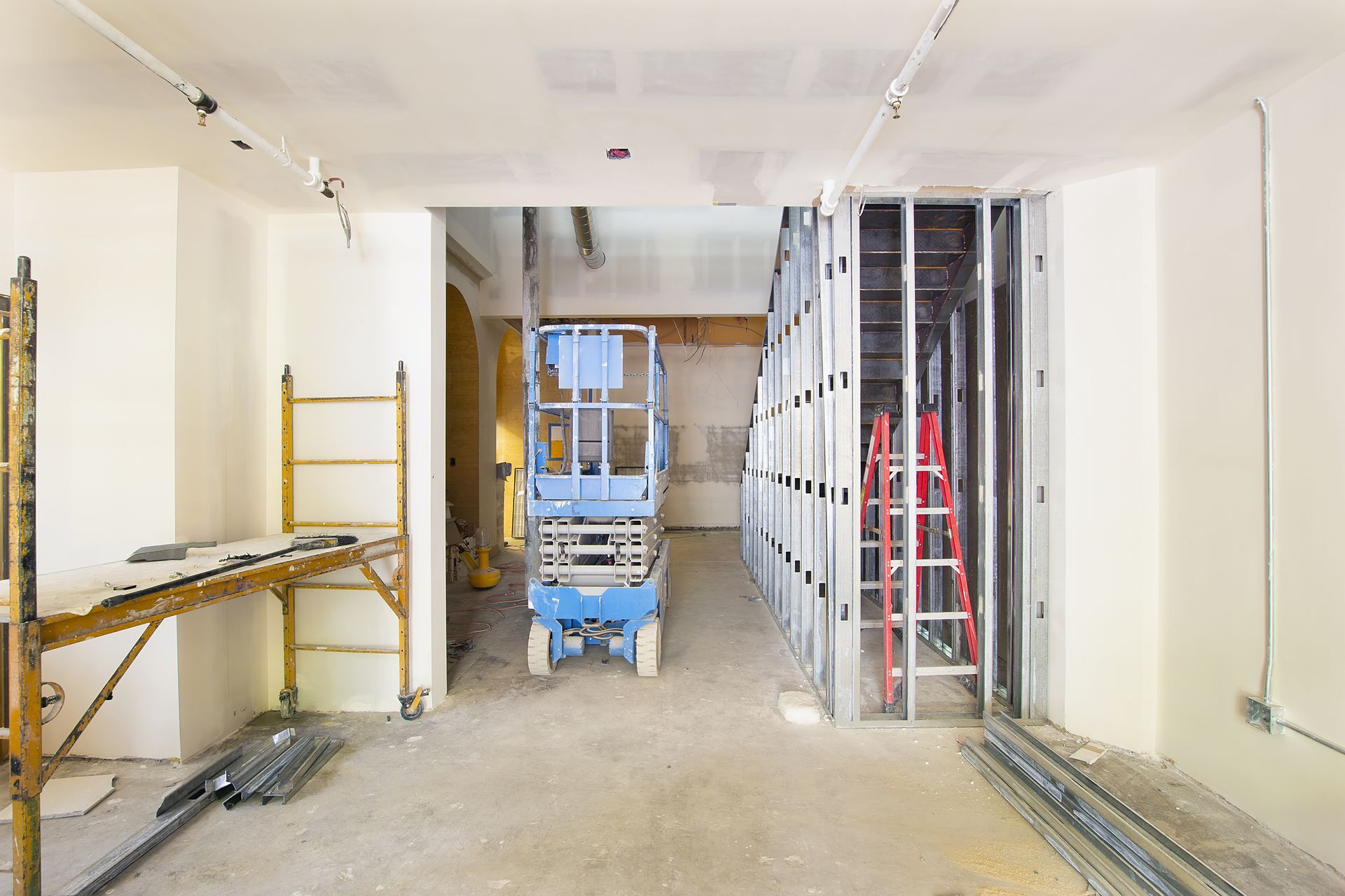 a blue scissor lift is parked in a room under construction .