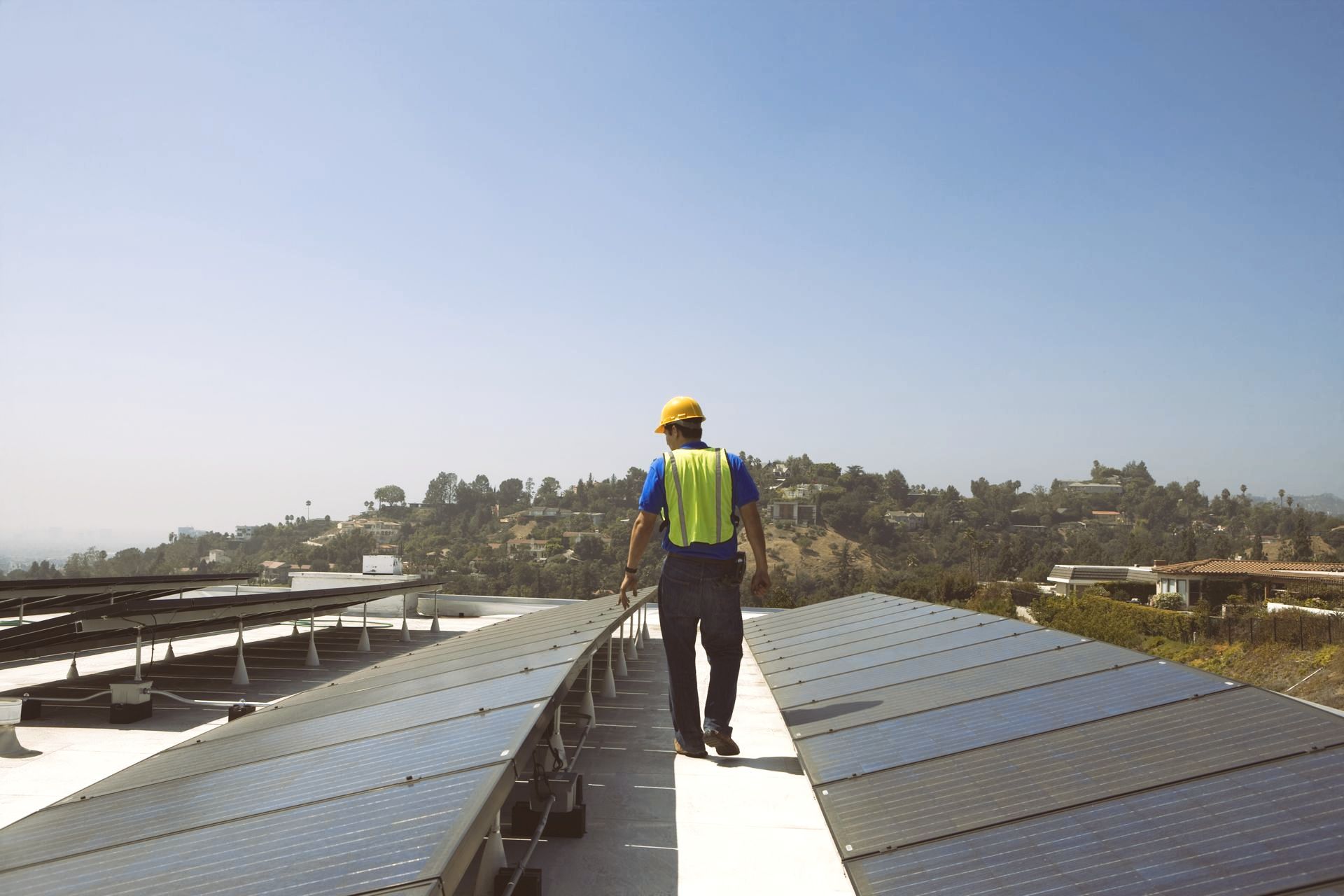 a man is standing on top of a roof with solar panels .