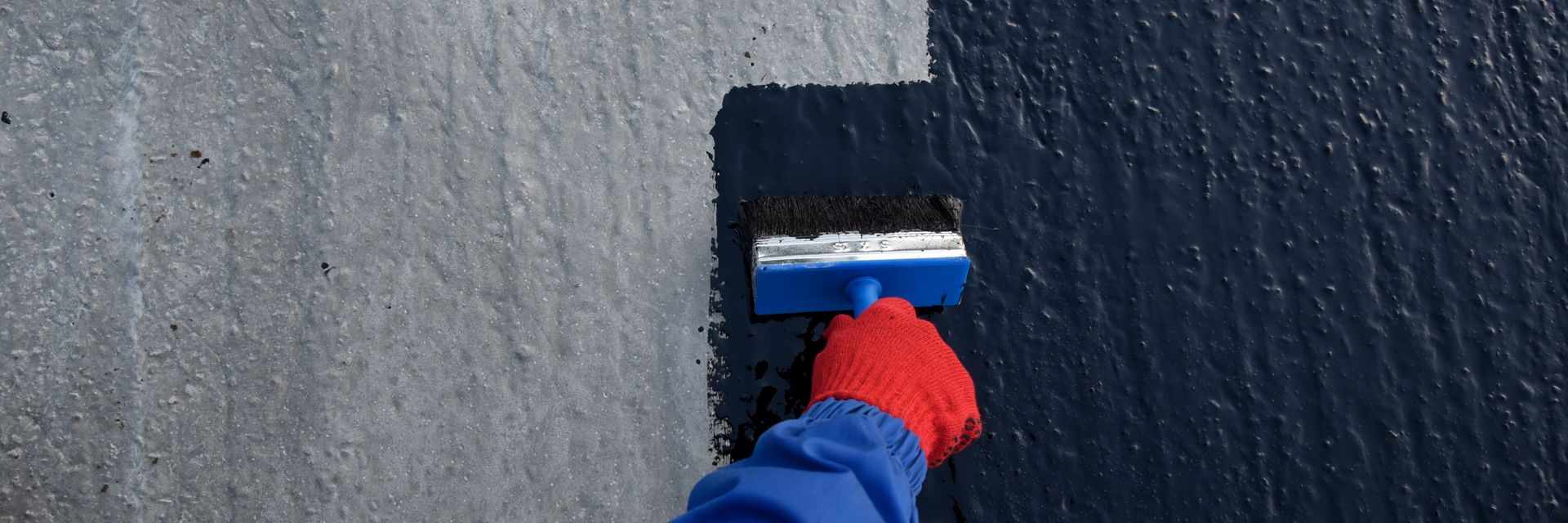 a person is painting a concrete surface with a brush .