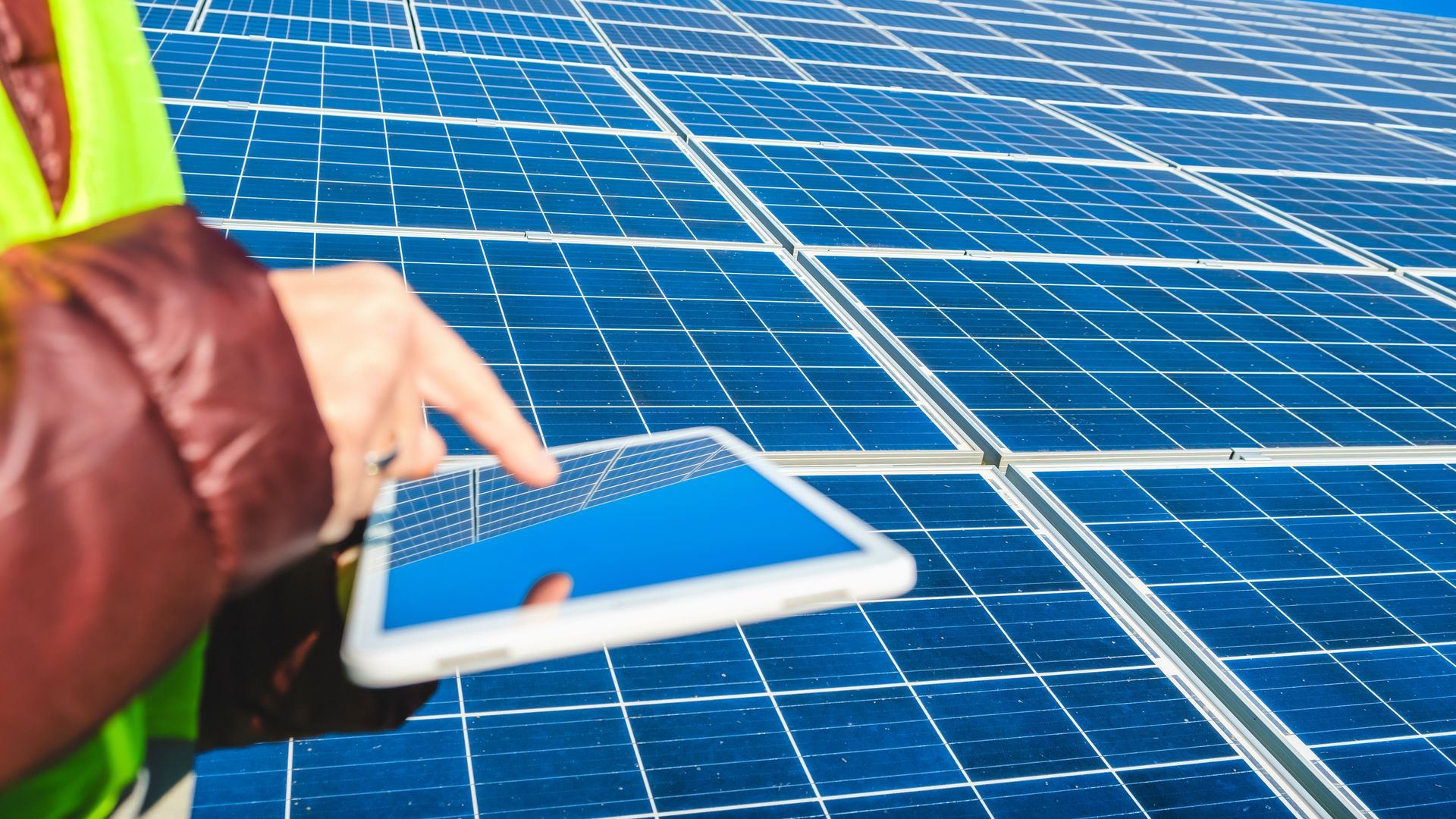 a person is holding a tablet in front of a solar panel .