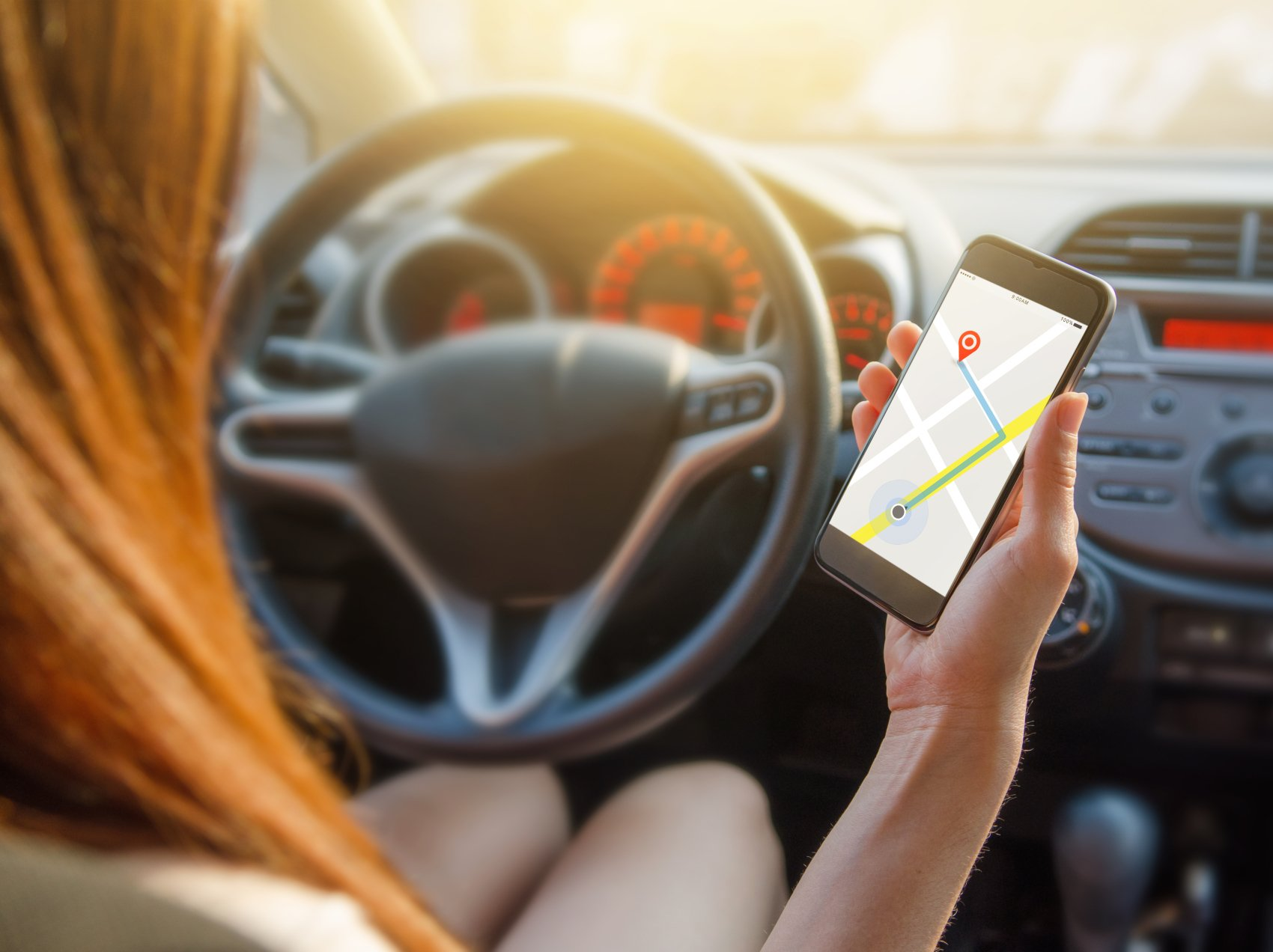 Woman Holding Phone with GPS directions in driver's seat of car
