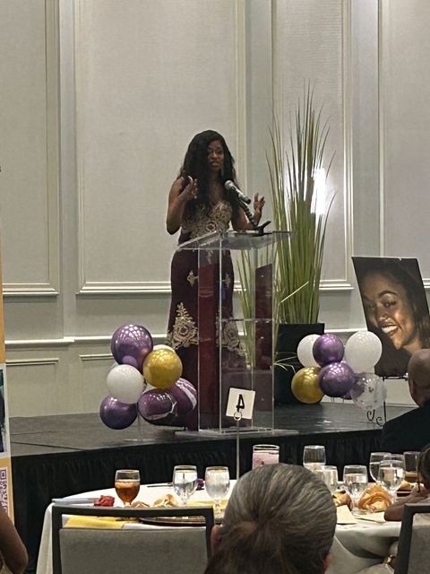 A woman is standing at a podium giving a speech to a group of people.