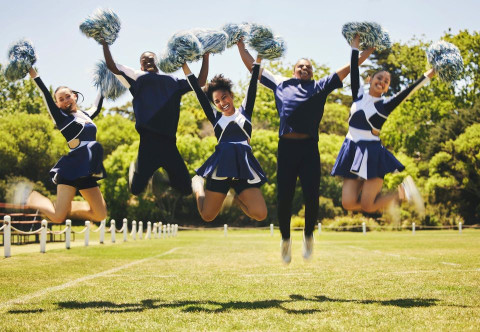 A group of cheerleaders are standing next to each other holding pom poms.