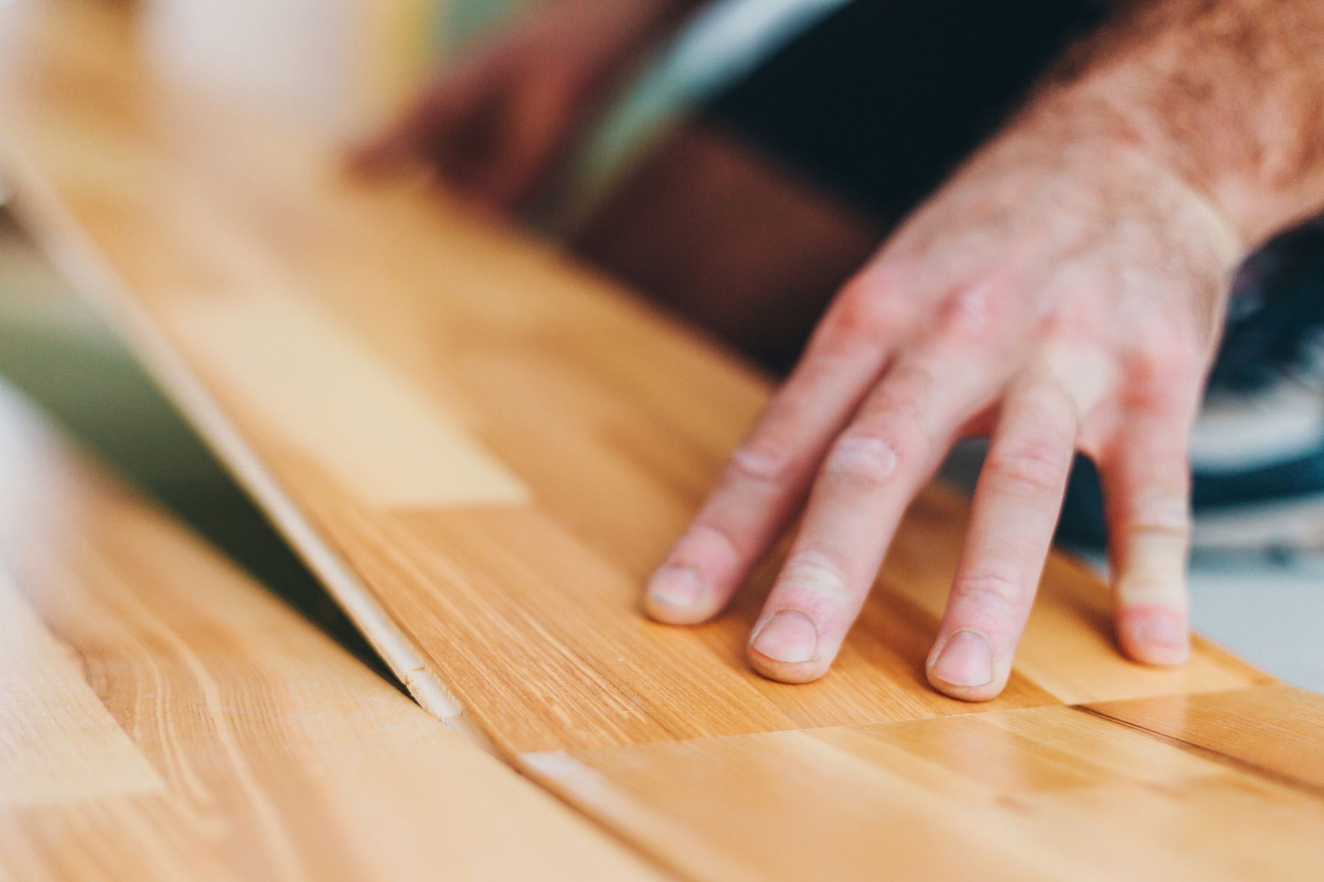 Close-up of a pair of hands that place a wooden parquet on a floor. Close-up of a pair of hands that place a wooden parquet on a floor.