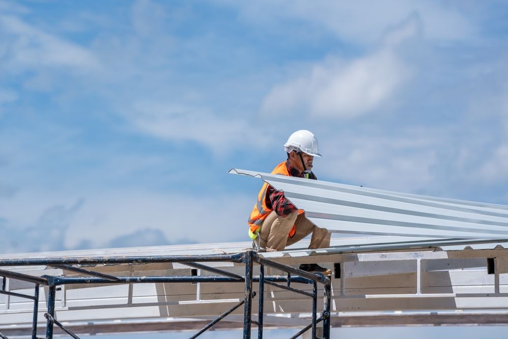 A Construction Worker Is Working On The Roof Of A Building — Sattin's Metal Roofing In Avondale, NSW