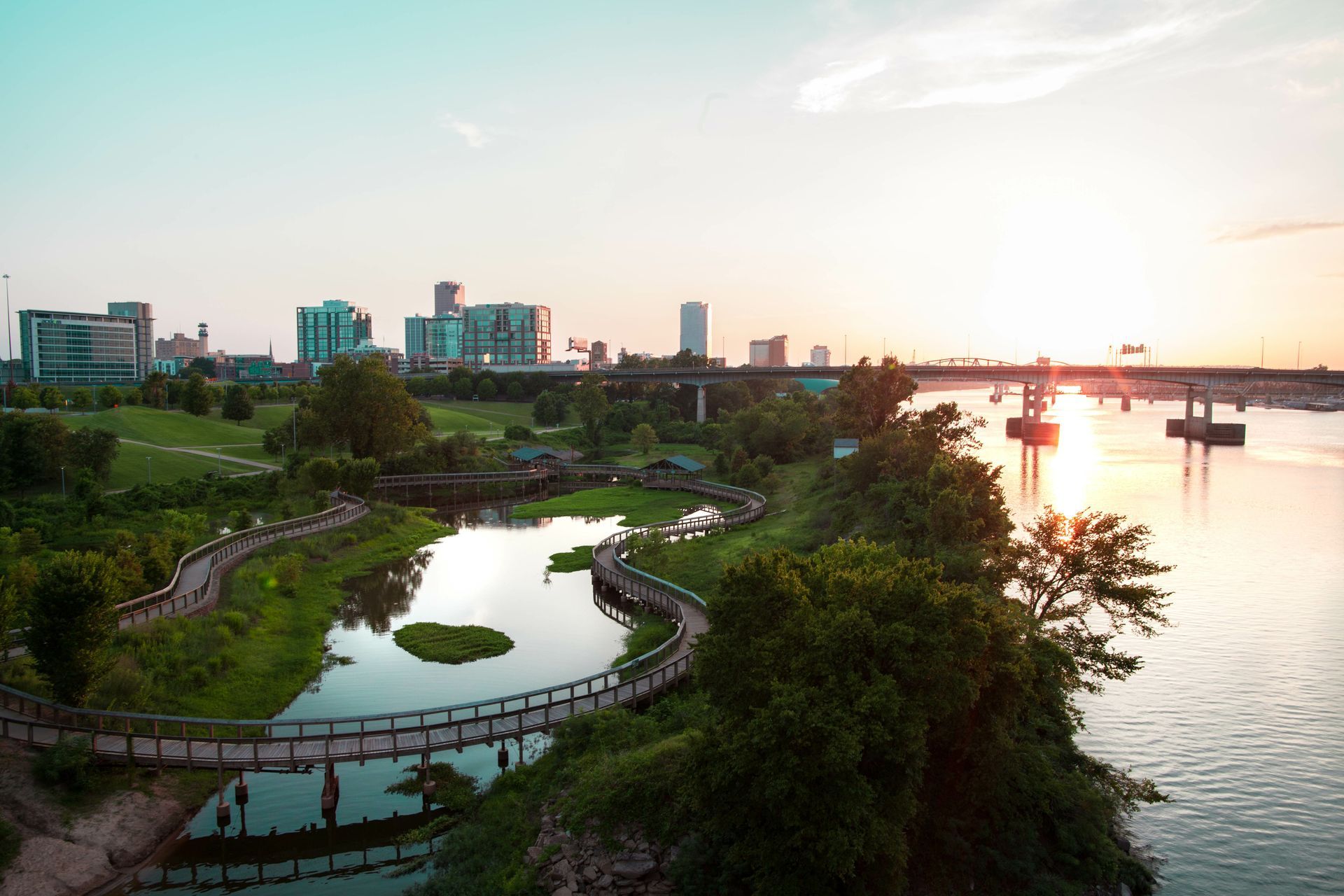 An aerial view of a river with a city in the background at sunset.