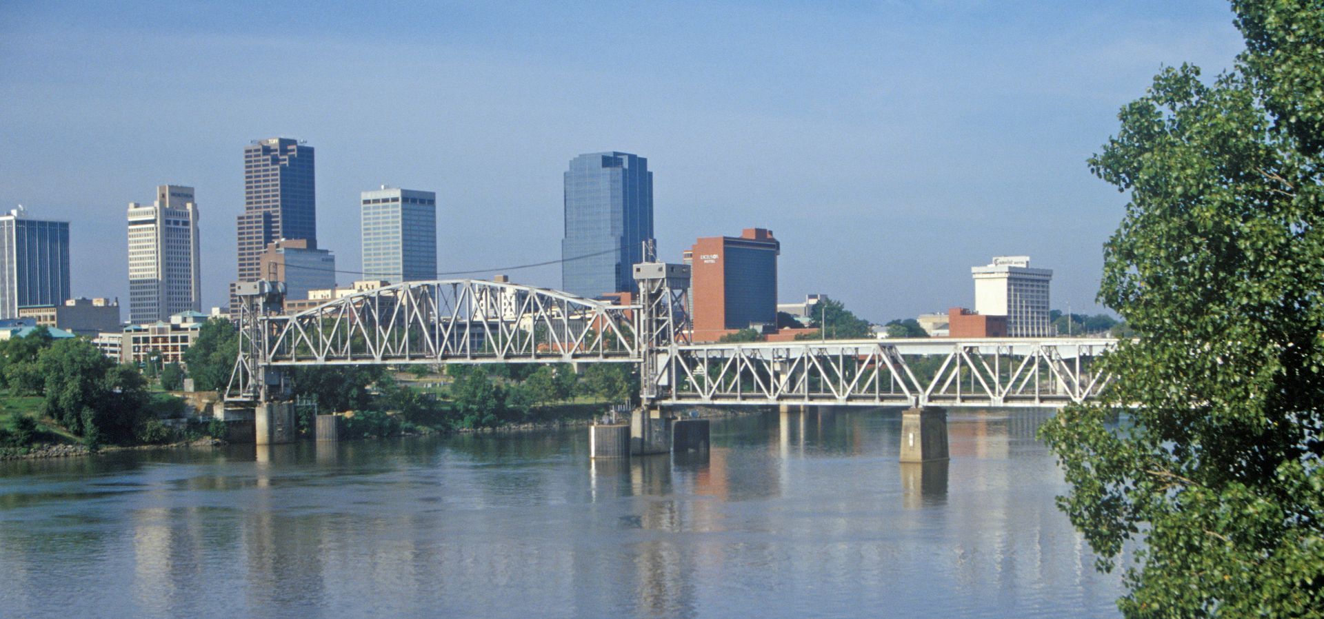 A bridge over a river with a city skyline in the background