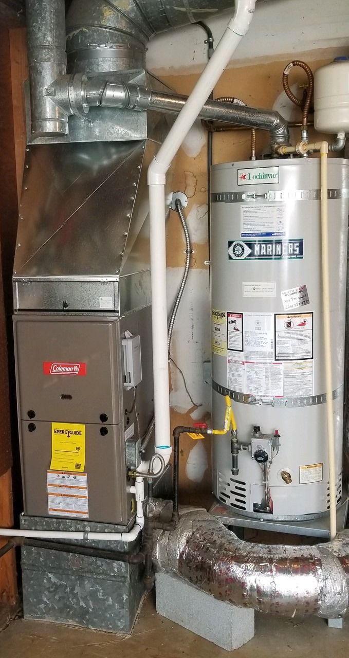 Furnace and hot water heater side-by-side in a utility room. Ductwork, gas lines, and venting are visible.