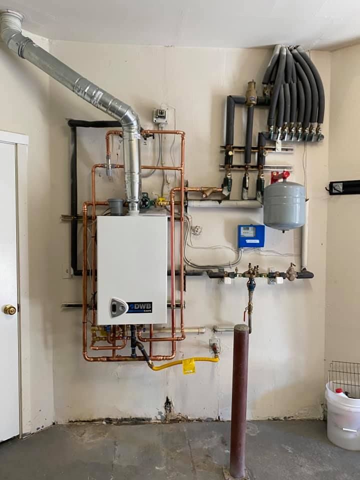 Heating system installed on a wall with copper pipes, a white boiler, and a vent.