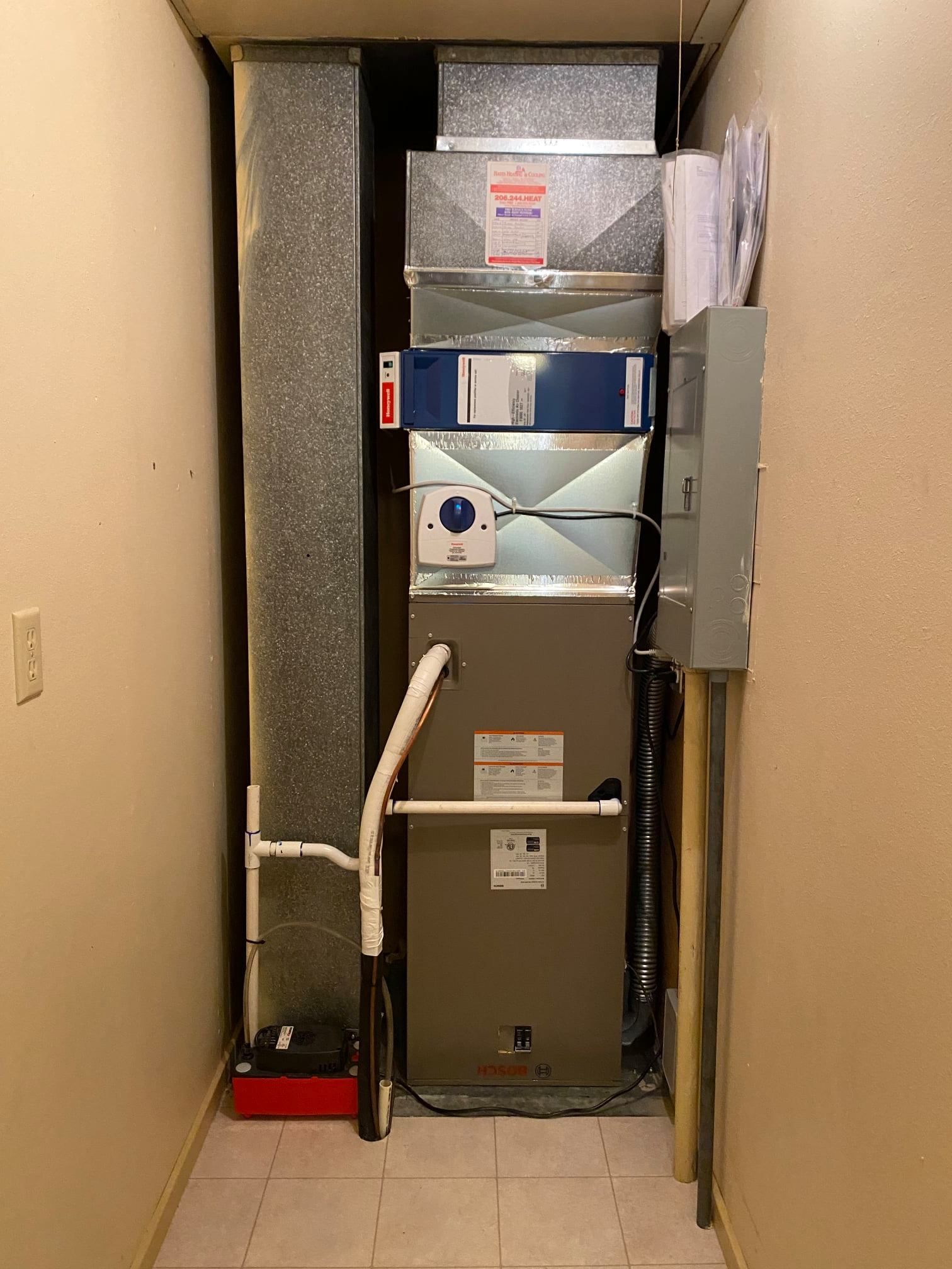 HVAC unit in a narrow space with ductwork, electrical panel, and some tools.