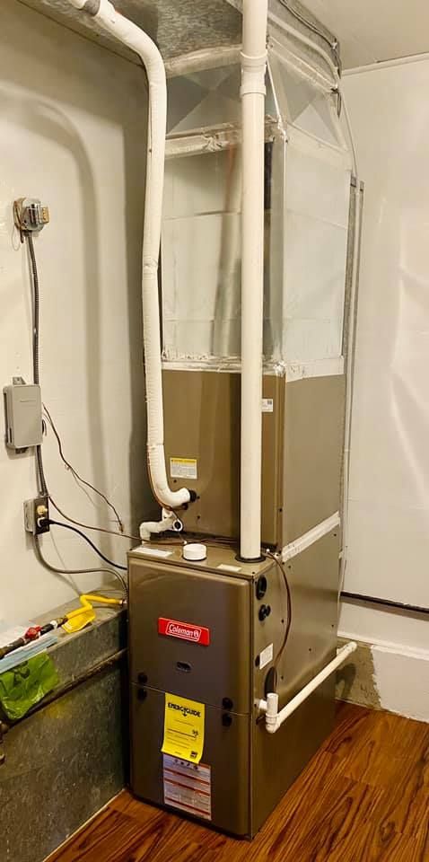 A Bryant furnace in a utility room with white pipes and ductwork. Electrical wiring on the wall.