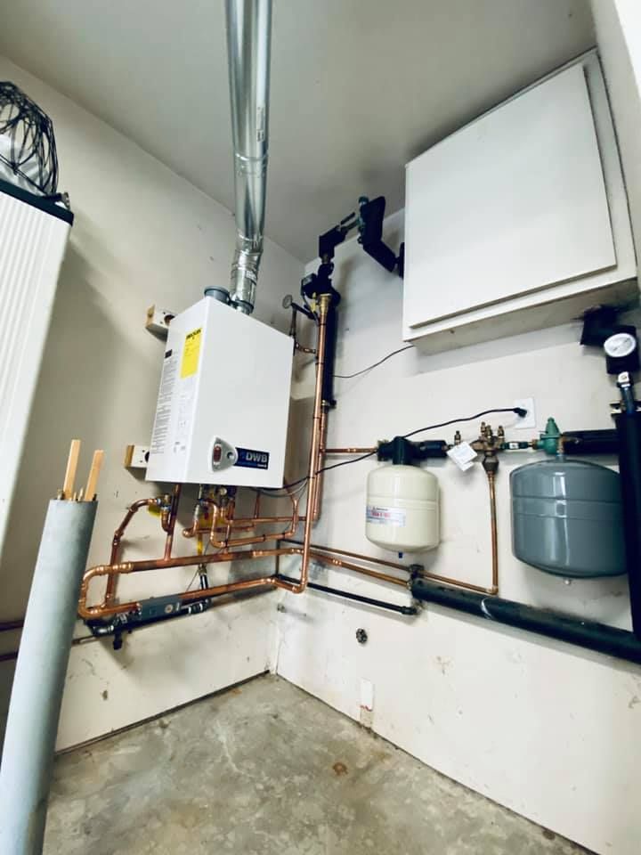 Gas water heater with copper pipes, vent, and expansion tanks in a utility room.