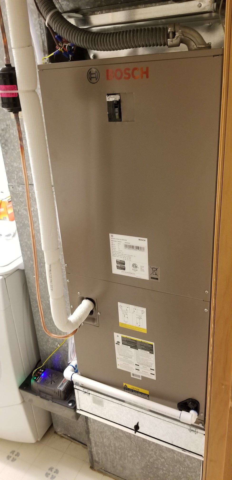 Bosch furnace in a utility room. Gray metal unit with white pipes and a black base.
