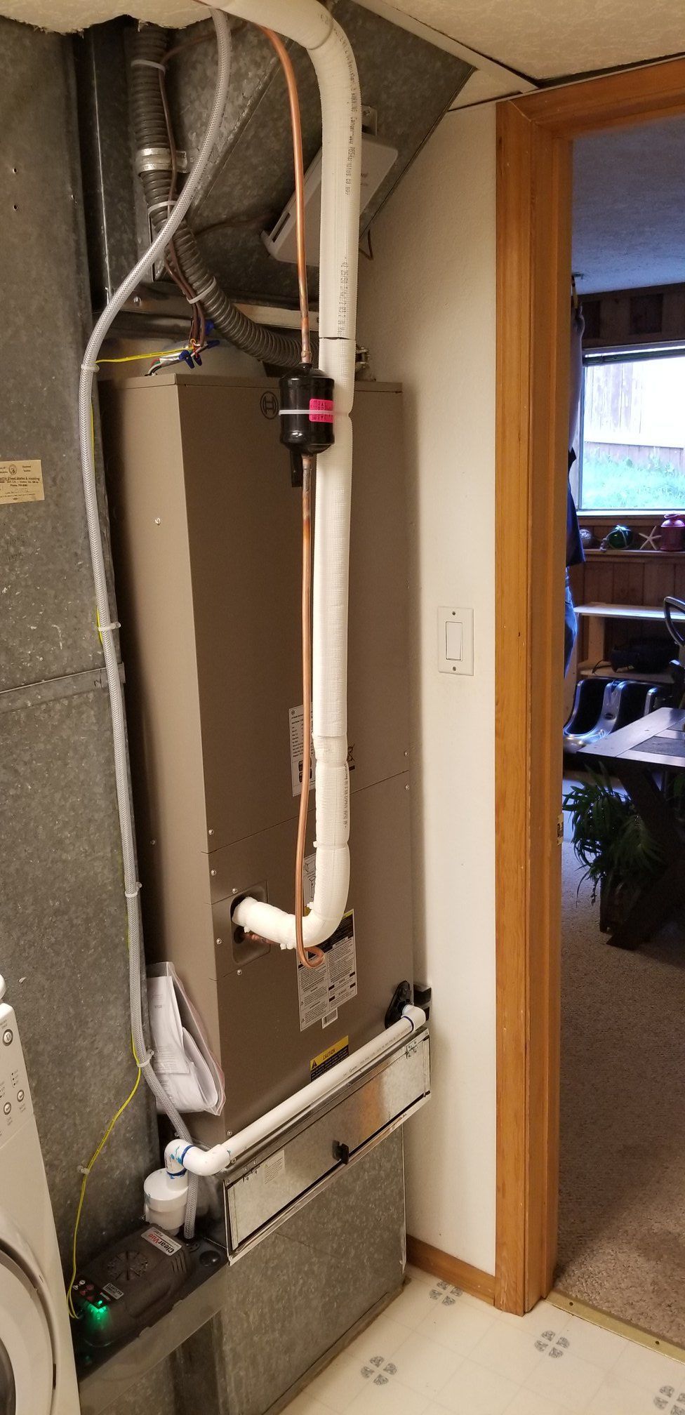 Furnace and ductwork in a basement near a doorway.