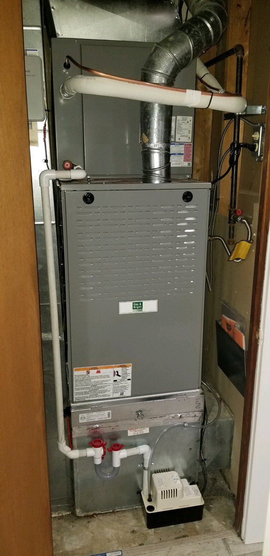 A furnace in a utility room with pipes and ducts.