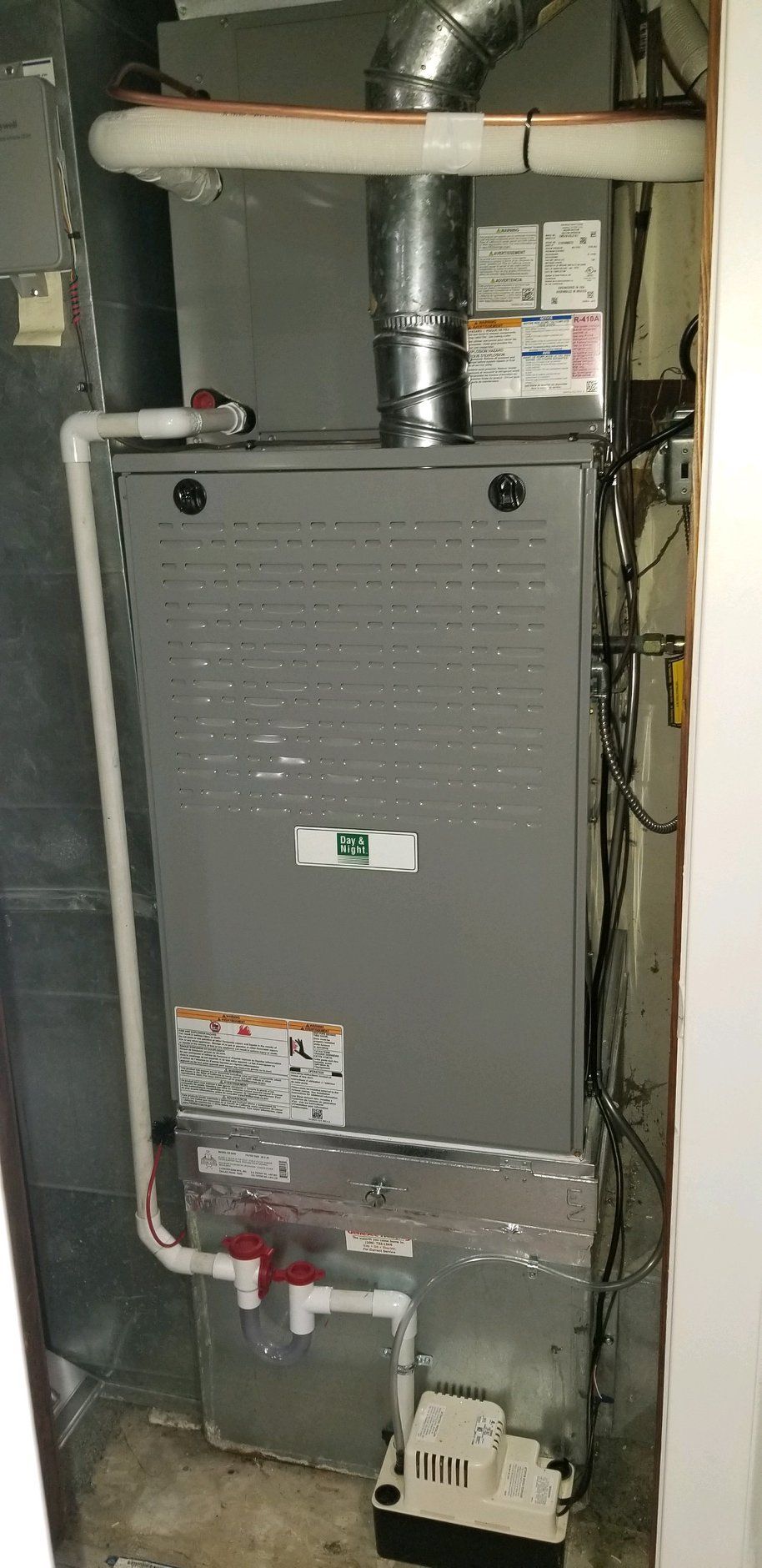 A furnace in a utility room with pipes and ductwork visible.