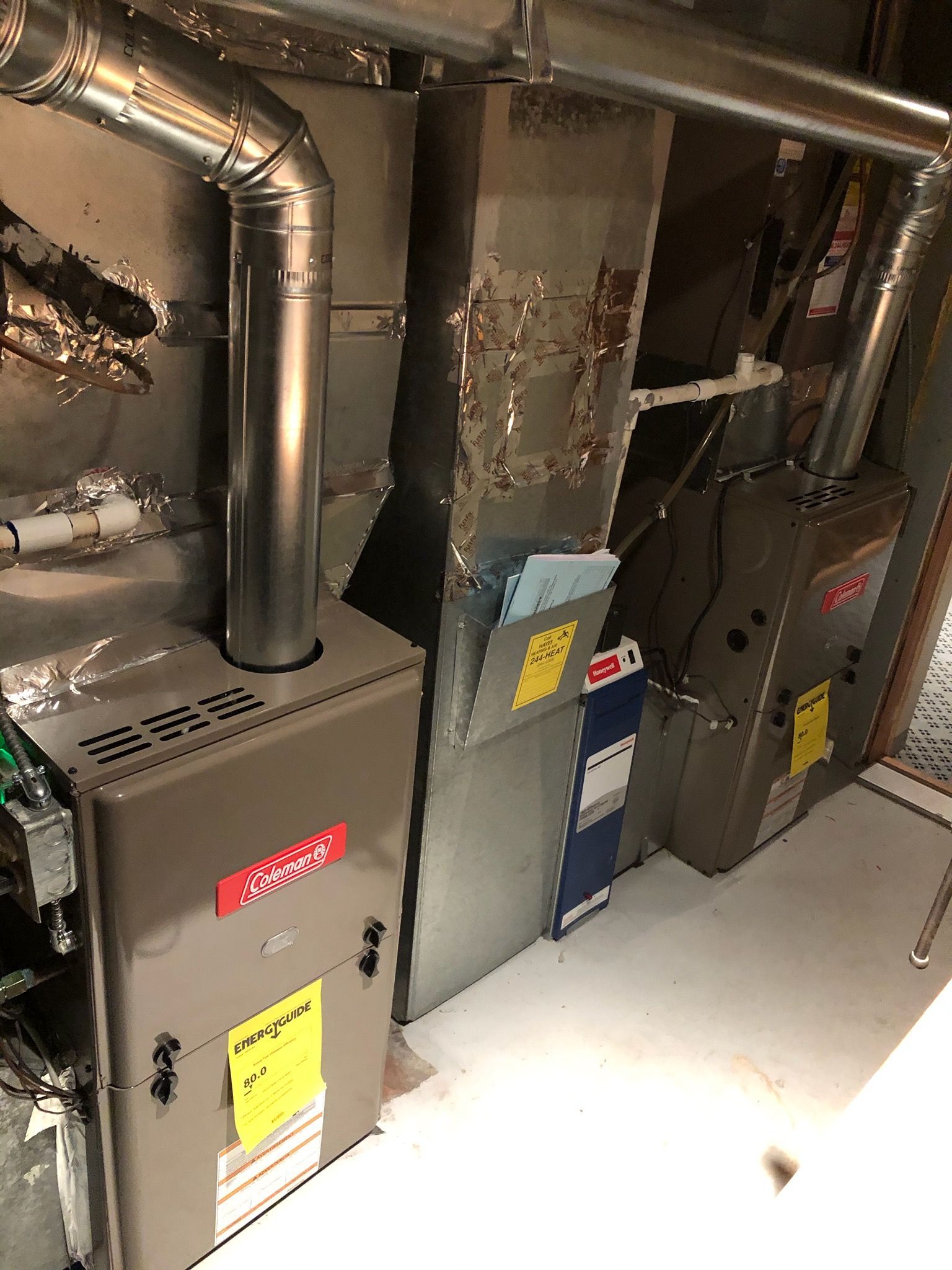 Two gas furnaces with ductwork in a basement setting.