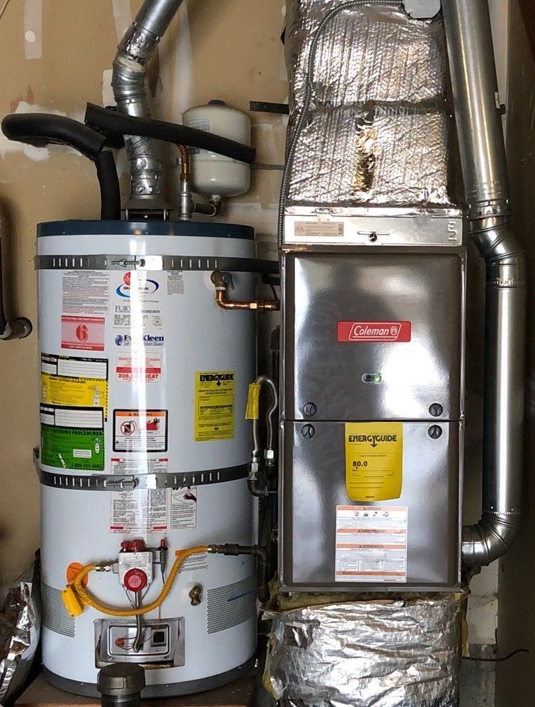 Water heater and Coleman furnace with connected vents in a utility room.