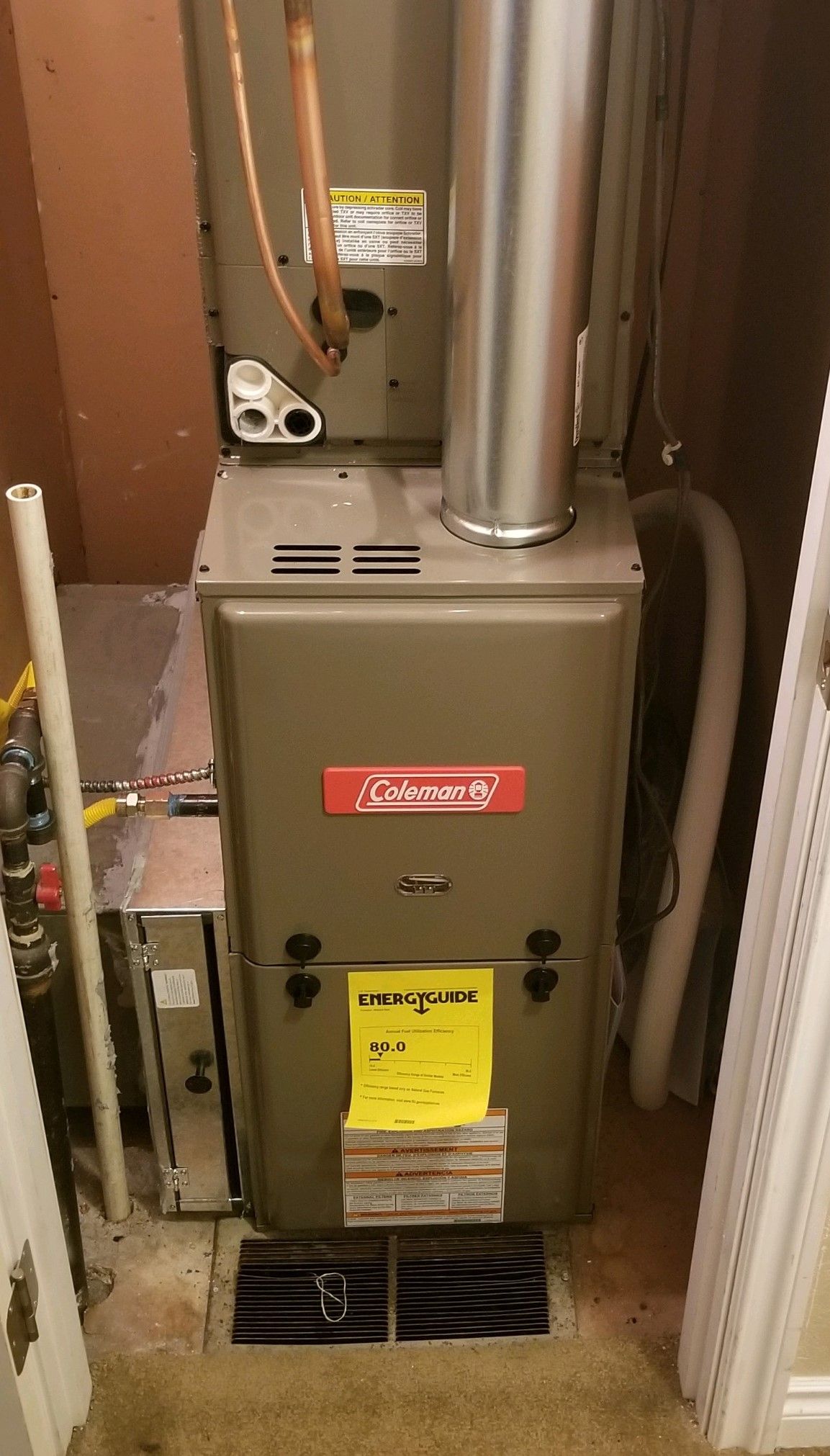 A Coleman furnace in a small room, with a flue and gas line visible.
