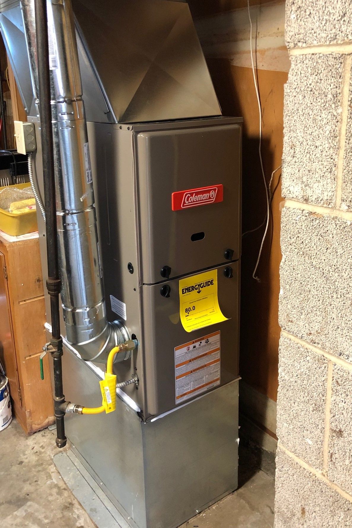 Furnace in a basement; gray metal, with ductwork and a gas line.  Energy efficiency sticker visible.