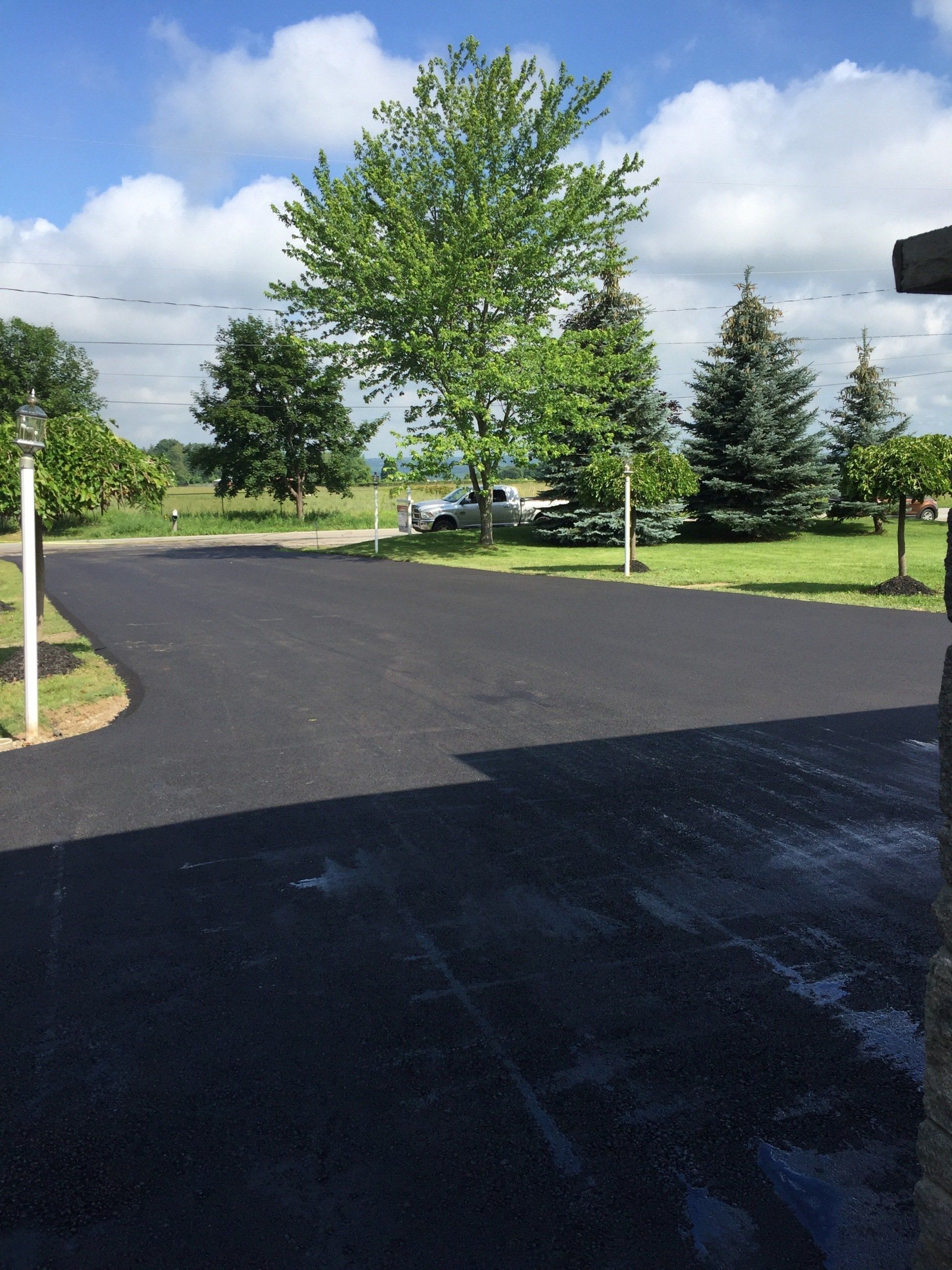 A driveway with trees and a blue sky in the background