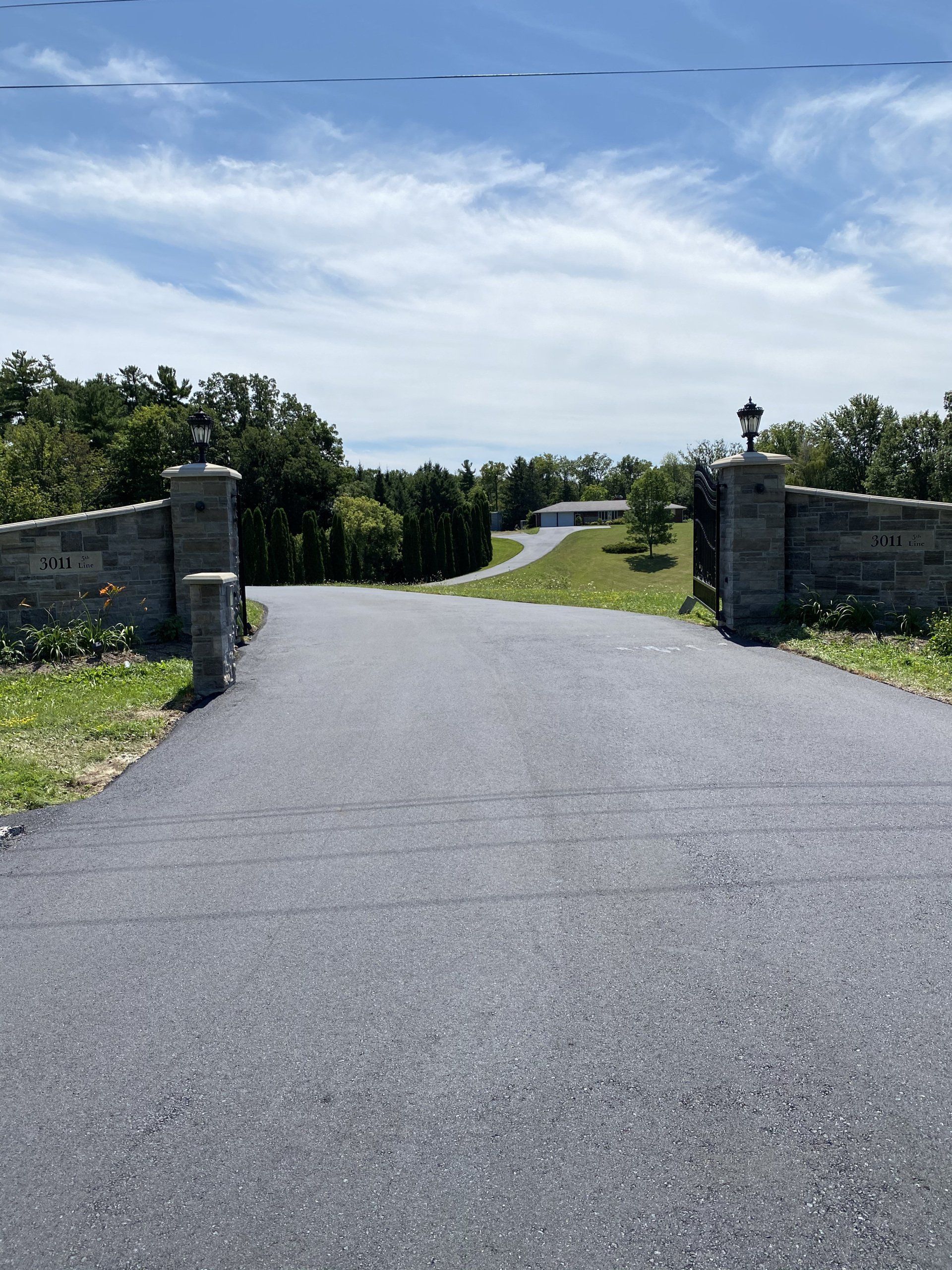 A driveway with a stone wall leading to a house.