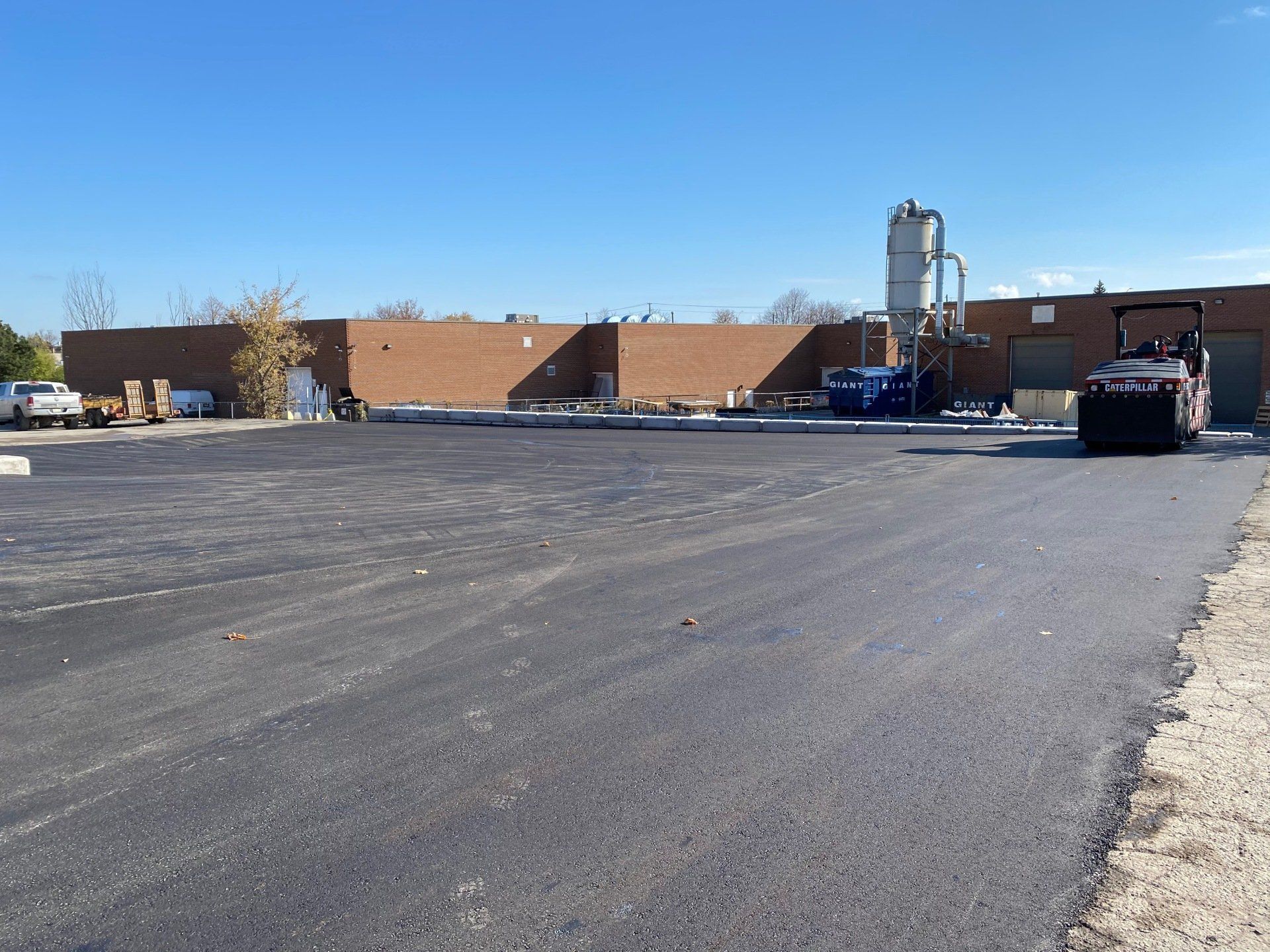 A large brick building is behind a large asphalt parking lot