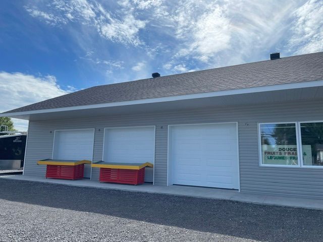 Une maison avec trois portes de garage et une grande fenêtre