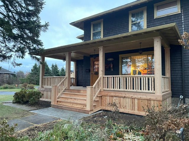 Une maison noire avec un porche et des escaliers en bois.