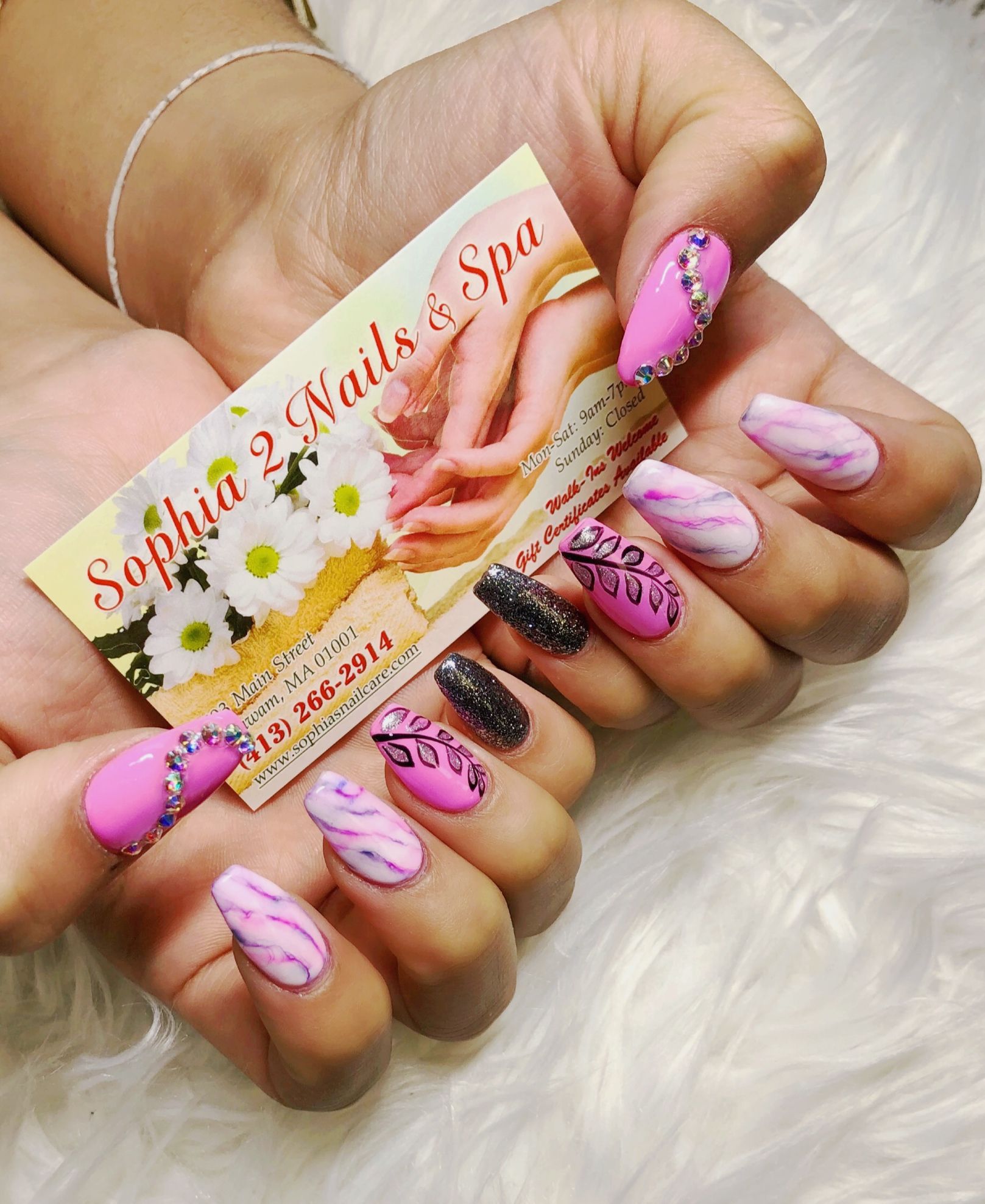a woman is holding a business card for sophia 2 nails & spa