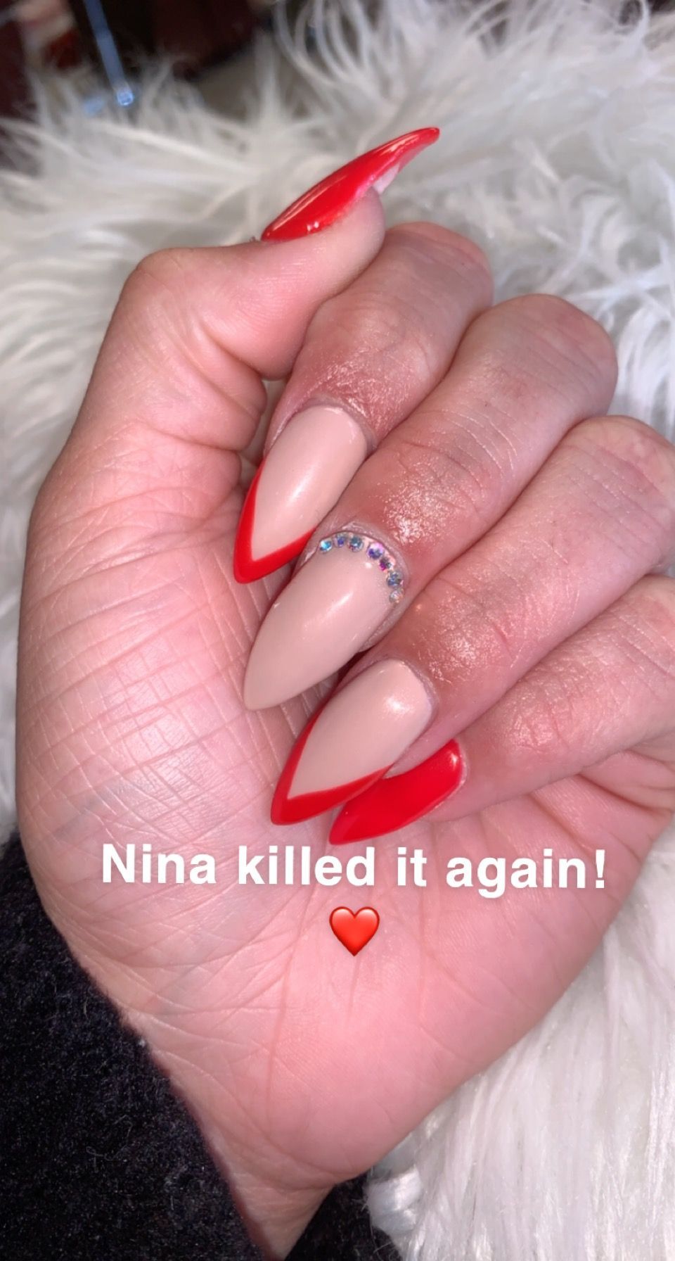 a close up of a person 's hand with long red nails .