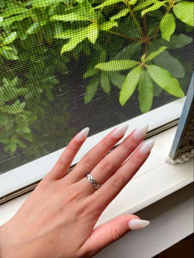a woman 's hand with a ring on it is sitting on a window sill .