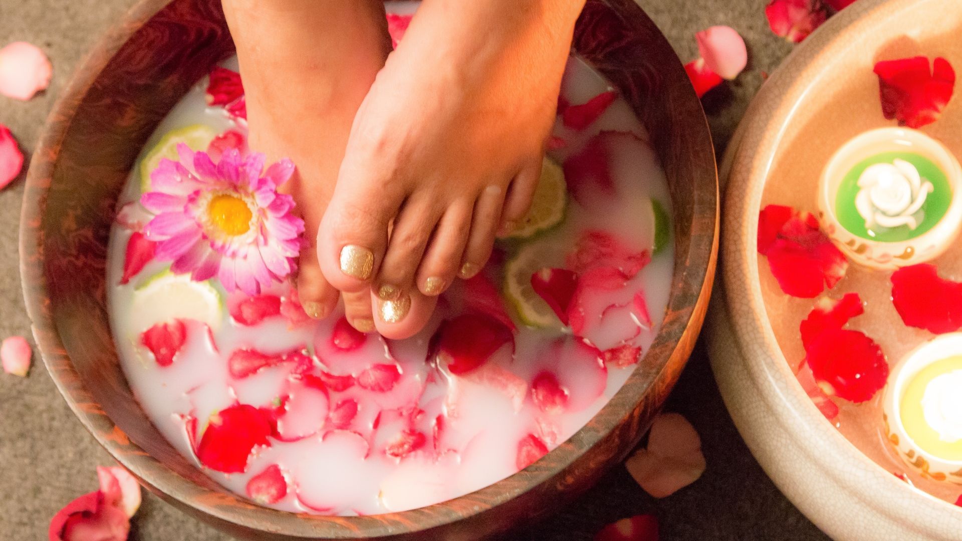 a woman 's feet are in a bowl of water with flowers .