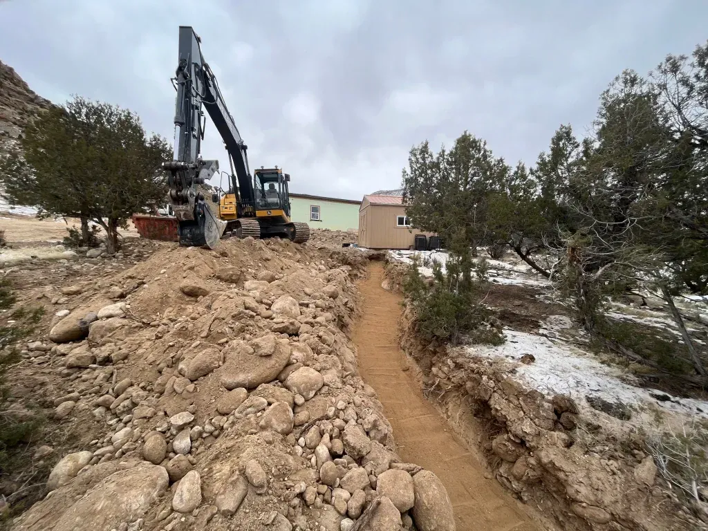 A large excavator is sitting on top of a pile of dirt.