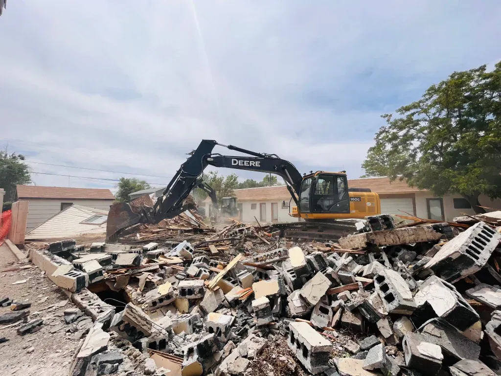A large excavator is demolishing a house in a residential area.
