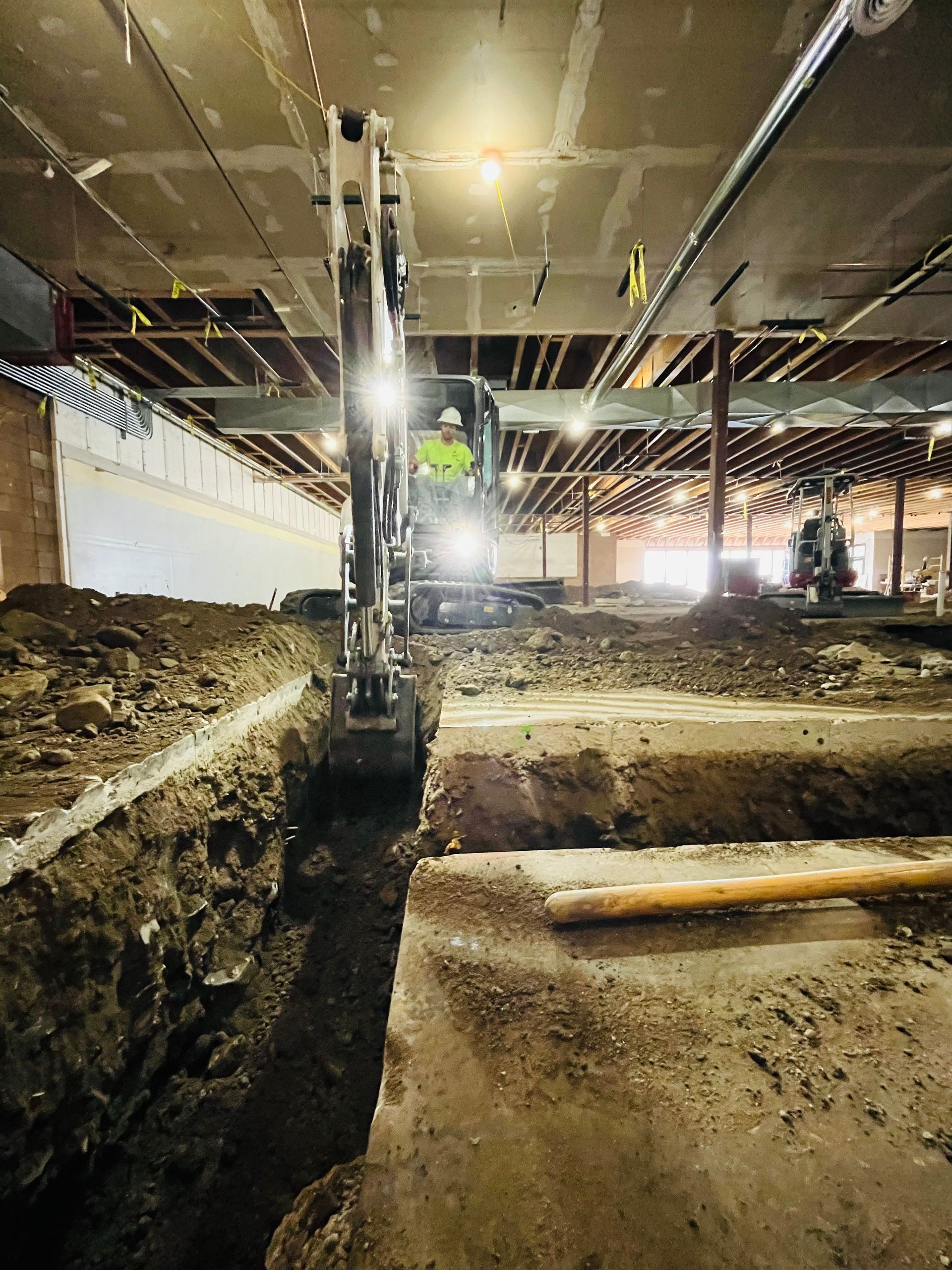 An excavator is digging a hole in the ground in a building.