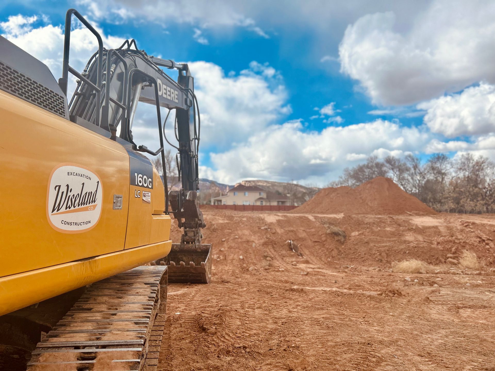 A yellow excavator is sitting on top of a dirt field.
