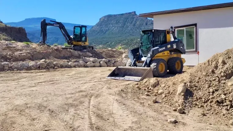 A bulldozer is moving dirt in front of a house.