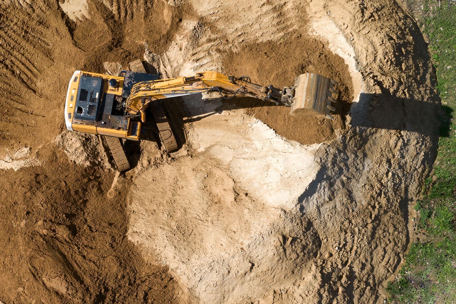 Construction site: Excavators loading dump trucks with dirt on a large, brown dirt field.