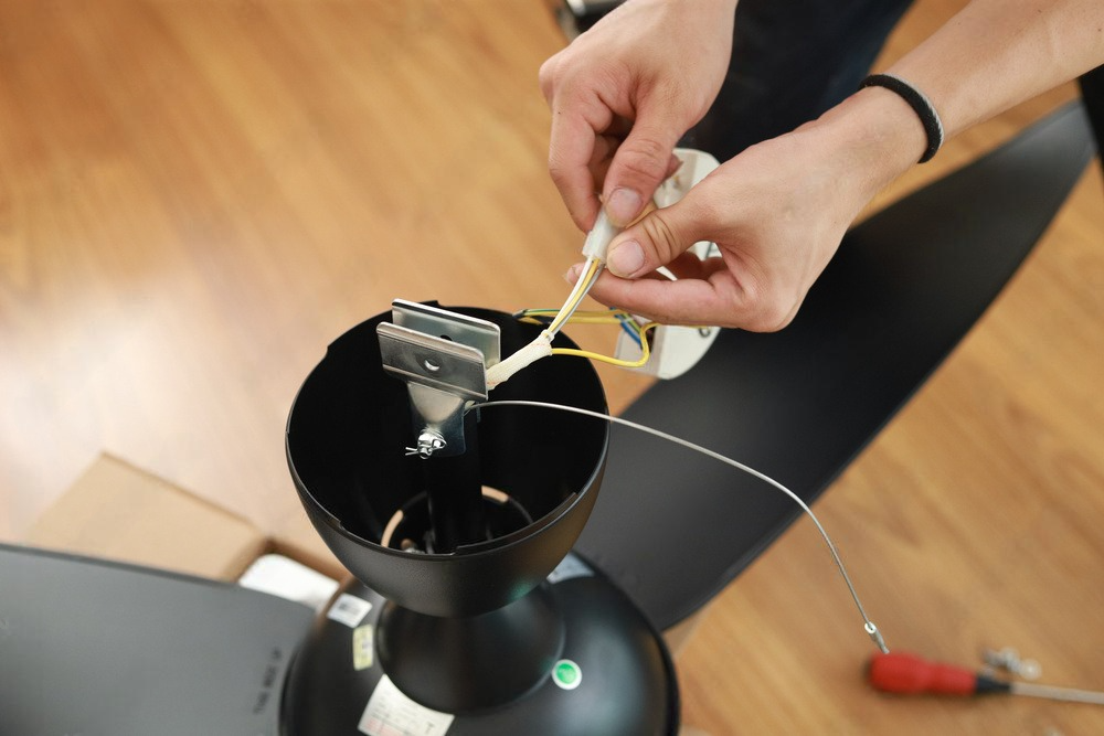 a person is fixing a ceiling fan with a screwdriver