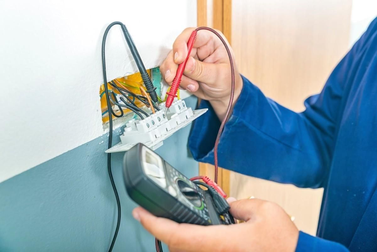 an electrician is using a multimeter to test a socket